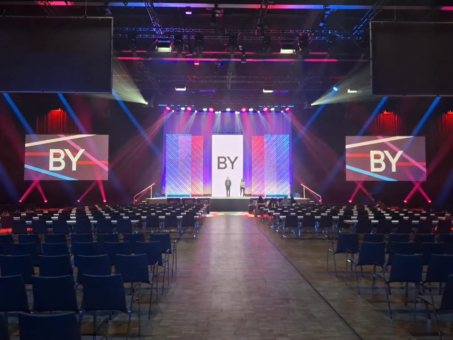 LED video wall and projection screens on a stage with lighting and seated audience area
