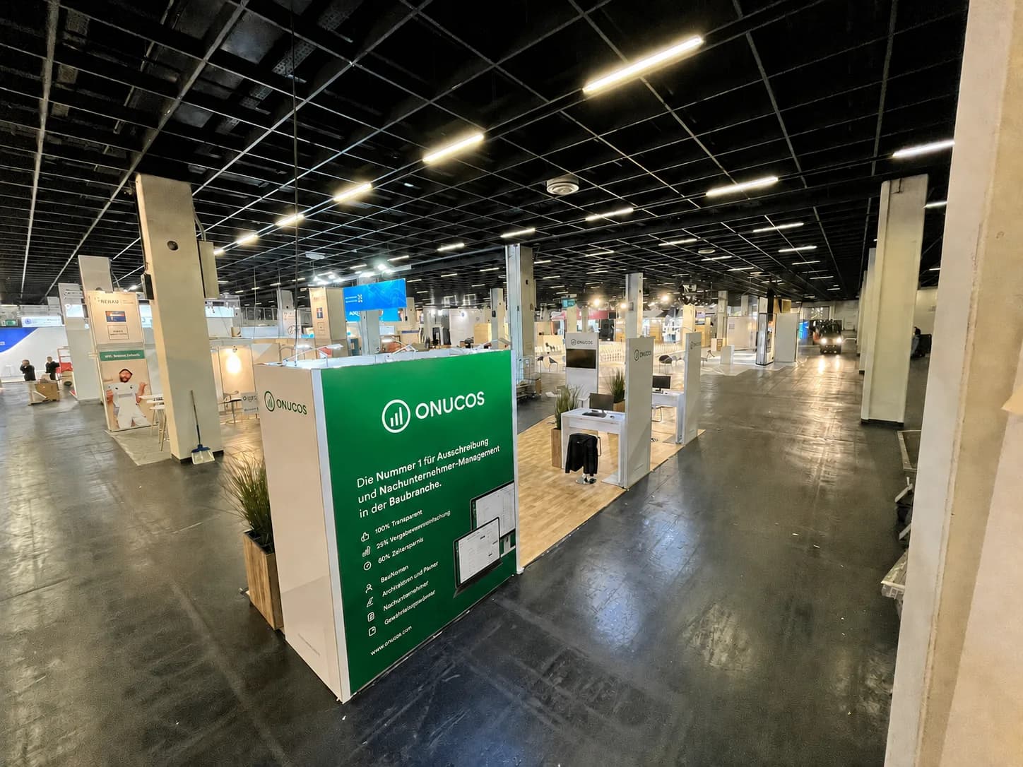 Modular stand with a large green graphics wall, timber floor and workstation with screen