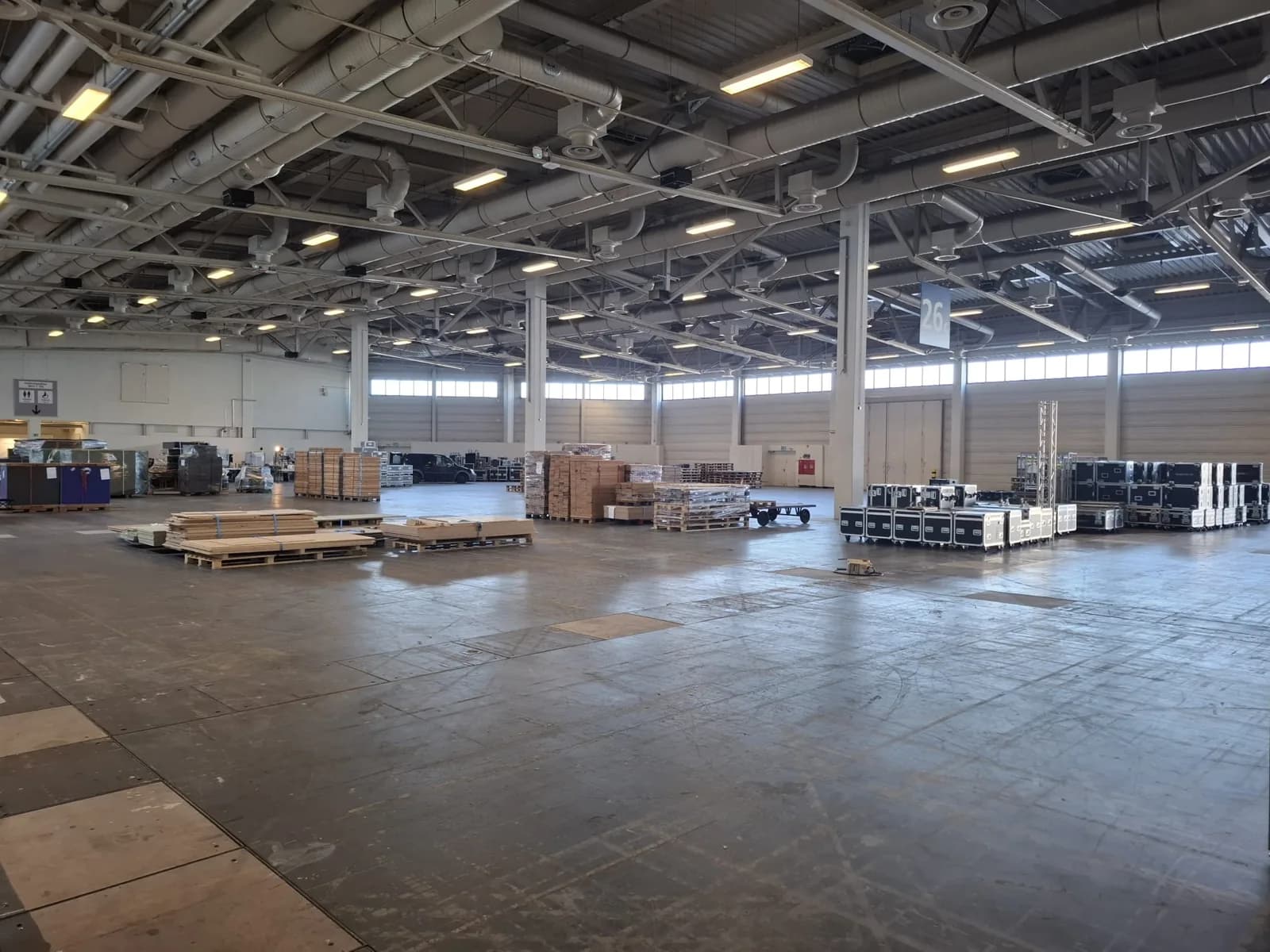 Exhibition hall during installation with transport crates, trusses and palletised stand materials