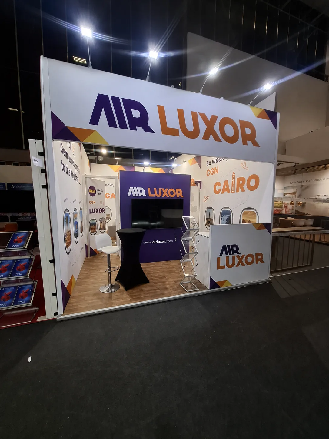 Inline stand with a high-level graphic fascia, screen wall, poseur table and brochure rack
