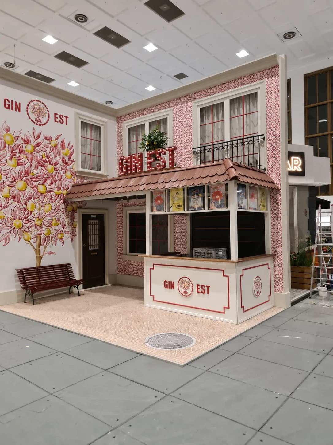 Custom exhibition stand designed as a shop front with a tiled roof, kiosk counter and patterned wall graphic